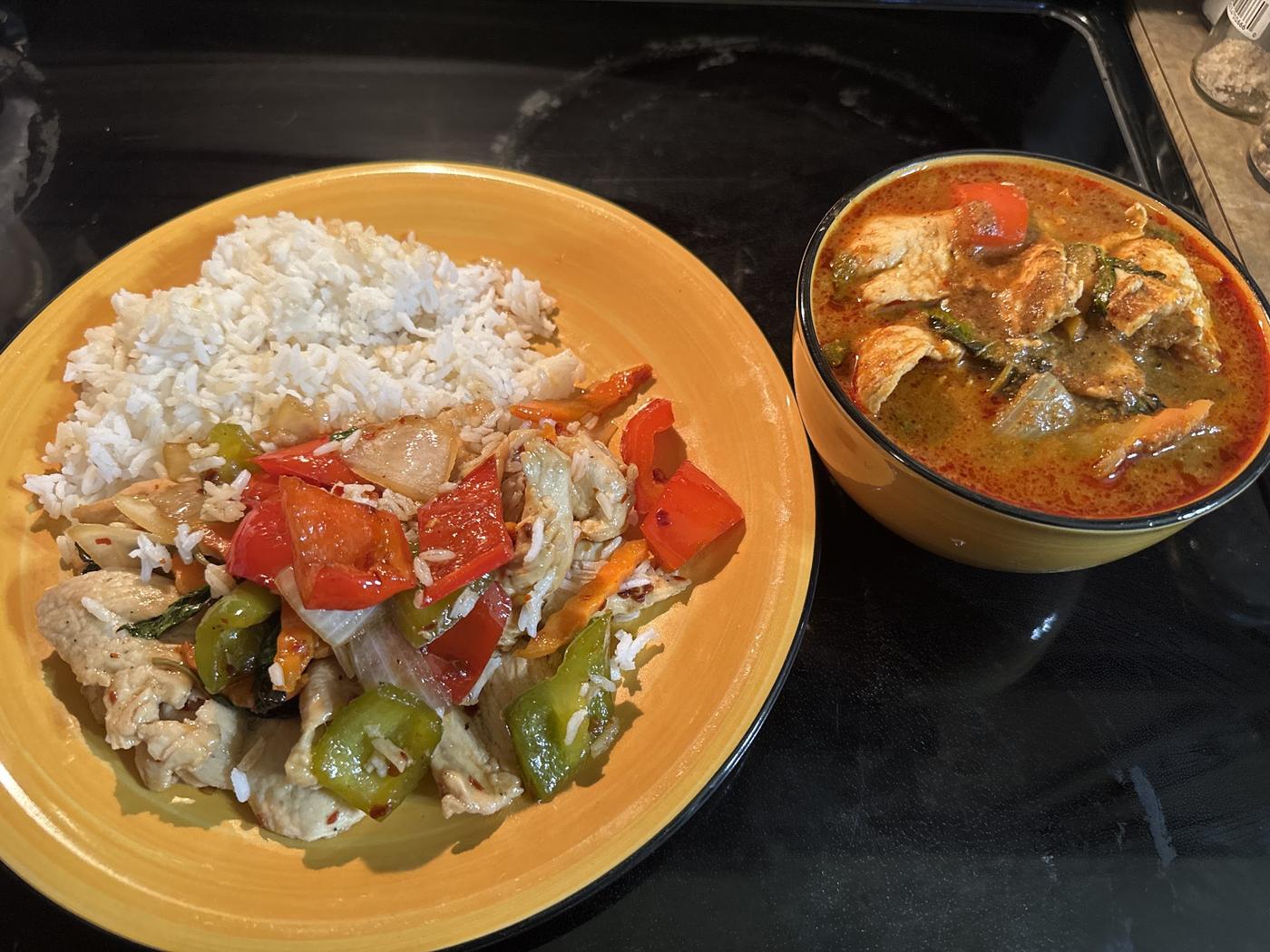 Basil chicken on an orange plate beside a bowl of red curry