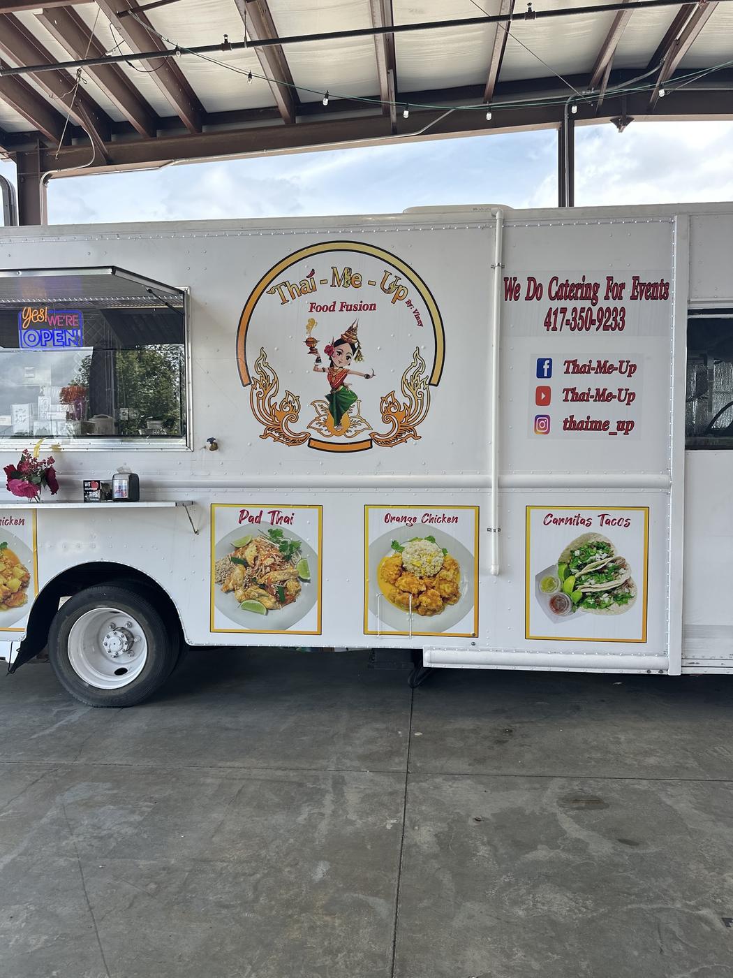 The side of the Thai-Me-Up truck showing the badge and the catering line