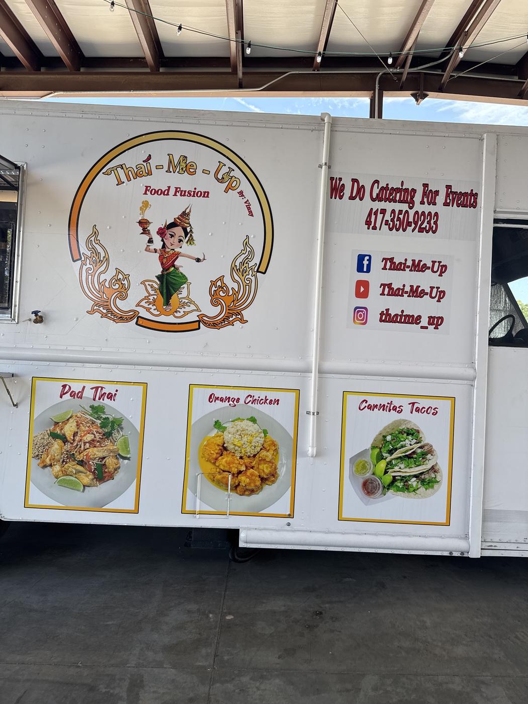 The Thai-Me-Up truck under the awning with its menu boards lit